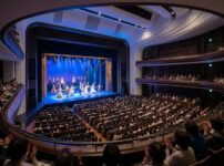 2027年の大阪でミュージカルが上演される、満員の観客と華やかなステージが印象的な大劇場の様子。