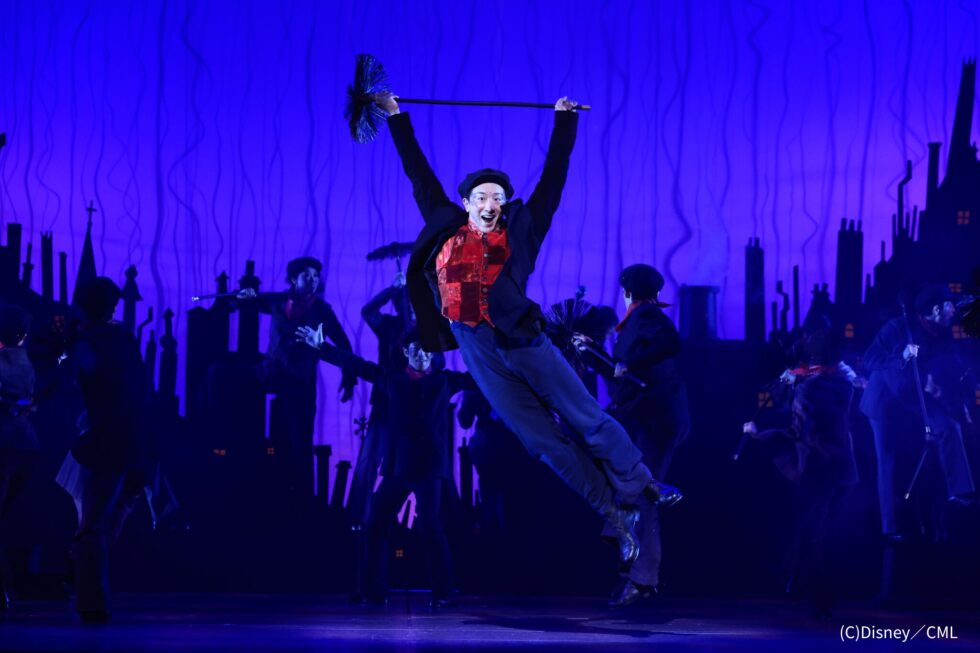 煙突掃除夫のバートが煙突ブラシを両手に持ち、舞台上で高くダイナミックにジャンプするダンスシーン