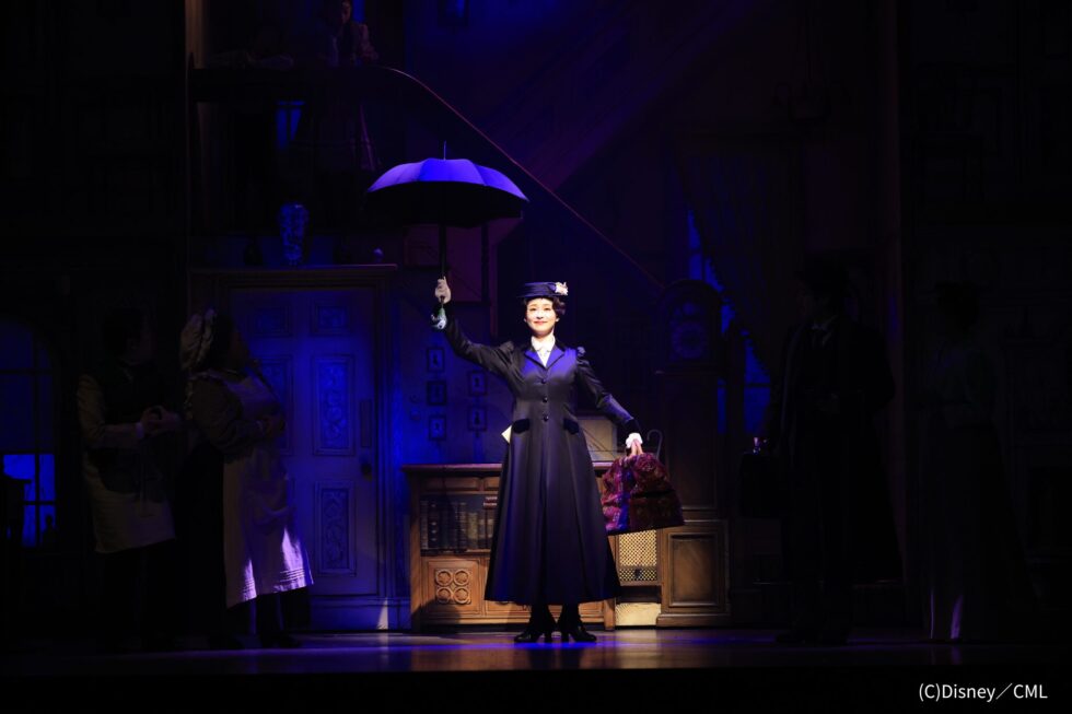 暗めの舞台上でピンスポットライトを浴び、トレードマークの傘を広げてふわりと宙に浮かび上がるメリー・ポピンズ