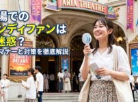 劇場の前でハンディファンを使って涼む若い女性ミュージカルファン