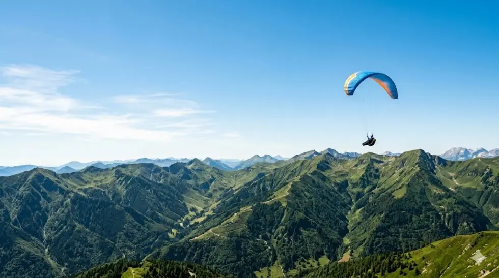 青空の下、緑豊かな山々の上空を気持ちよく飛ぶパラグライダー。ミュージカル『最強のふたり』の名シーンを表現したイメージ画像。