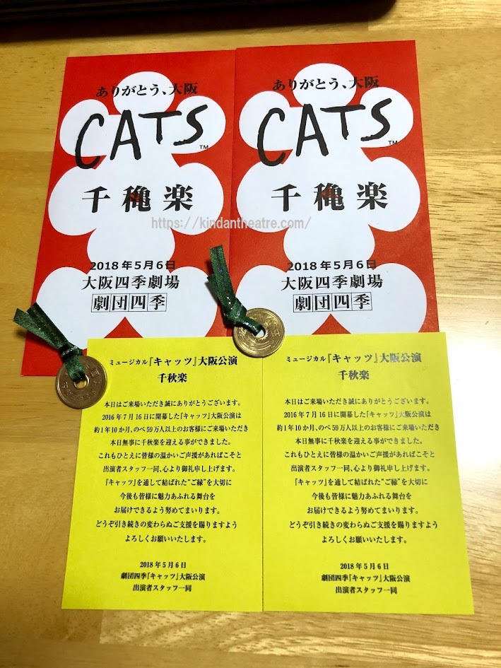劇団四季『キャッツ』大阪公演（2018年）の「千穐楽」と書かれた五円玉付き大入袋と、「千秋楽」お礼状が書かれた黄色のカード。机の上に置かれている。