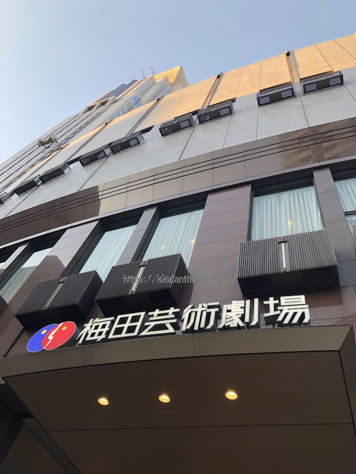 大阪公演の主催である梅田芸術劇場の正面玄関。劇場名が日本語で書かれた大型の看板やロゴが見える、夕暮れの様子。
