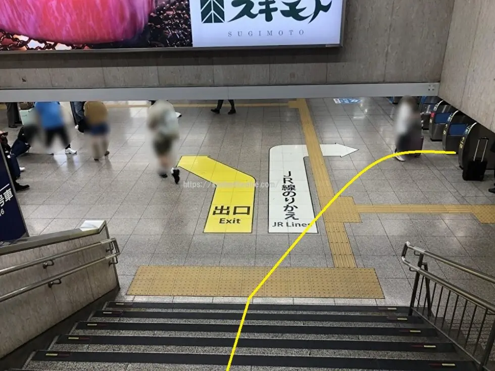 南口階段の途中、JR線乗り換えの案内サインと乗り換え改札を見渡す写真。