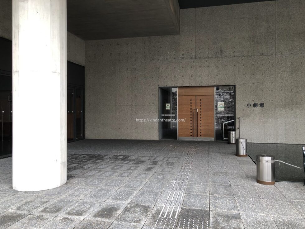 コンクリートの壁面と木製の扉が特徴的な小劇場（新国立劇場）の入り口