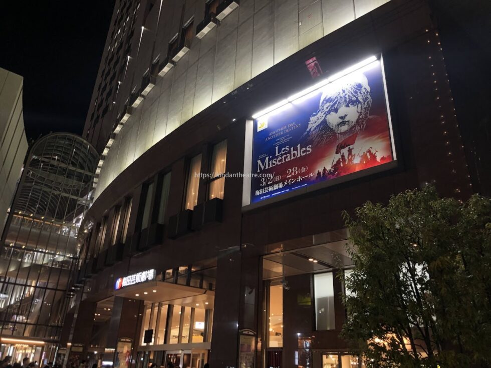 ミュージカル『レ・ミゼラブル』の巨大な電飾看板が輝く夜の梅田芸術劇場の外観
