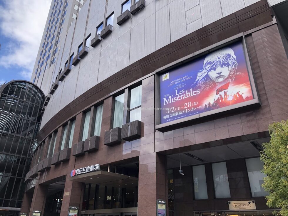 ミュージカル『レ・ミゼラブル』の大型サイネージが表示されている昼間の梅田芸術劇場外観